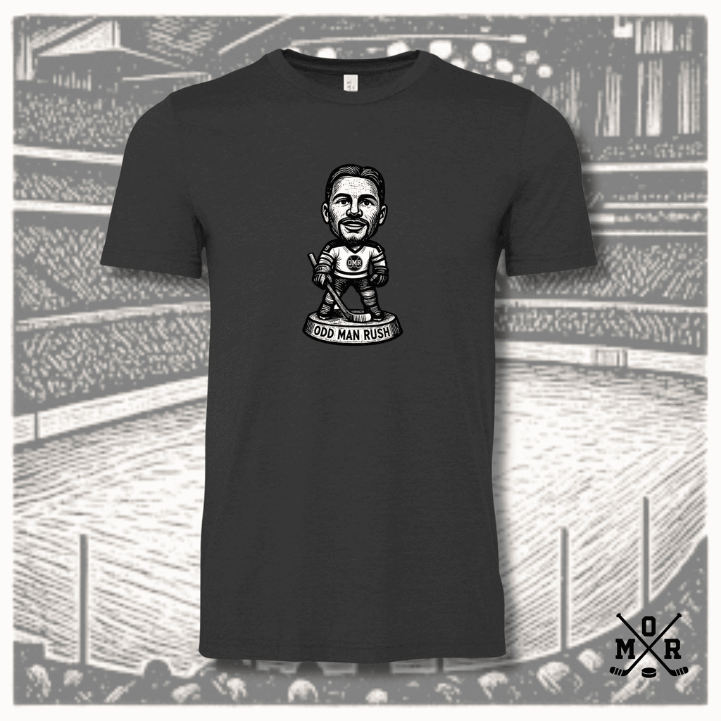 Charcoal grey t-shirt featuring odd man rush hockey bobblehead graphic on arena background